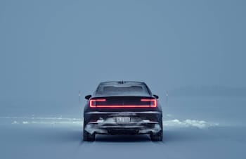 Black Polestar 2 from behind driving in a winter landscape 