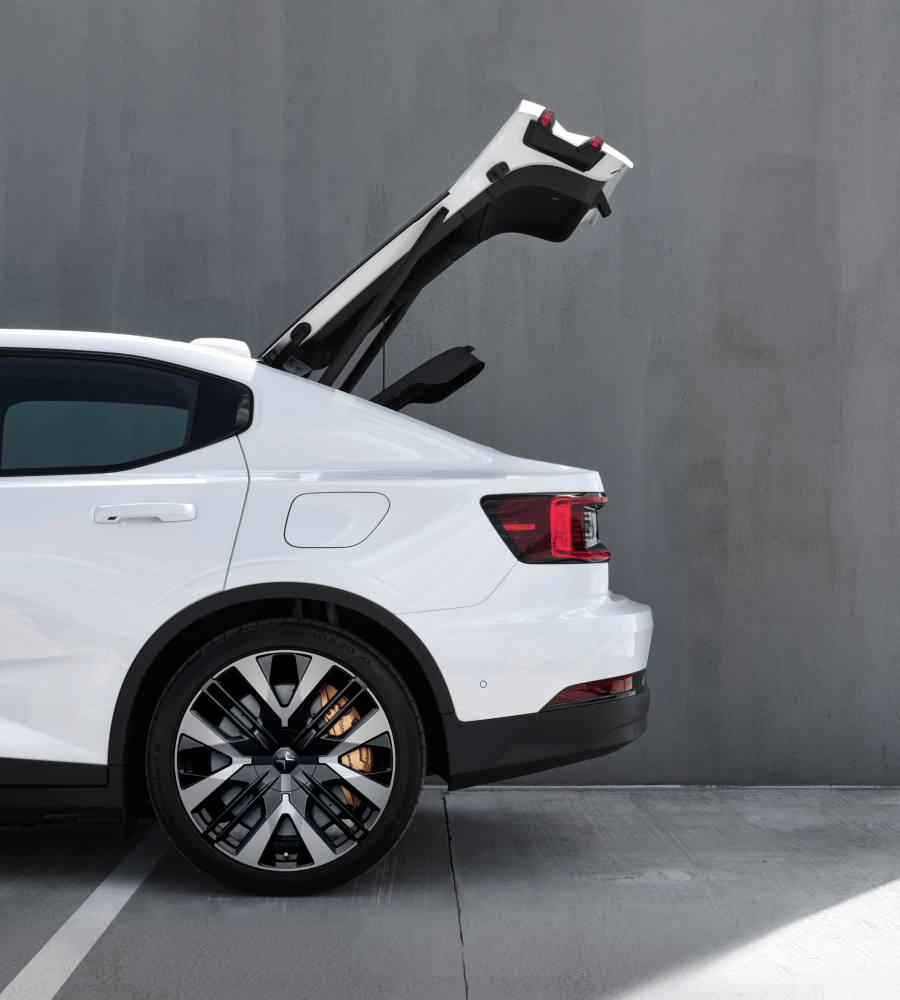 Rear side view of white Polestar 2 with tailgate opened.