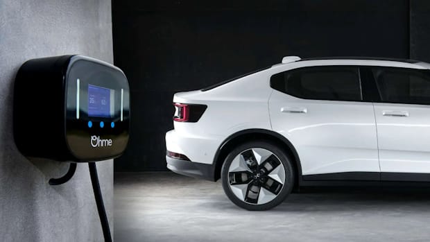 White Polestar 2 from the side with a charging box on the wall next to it.