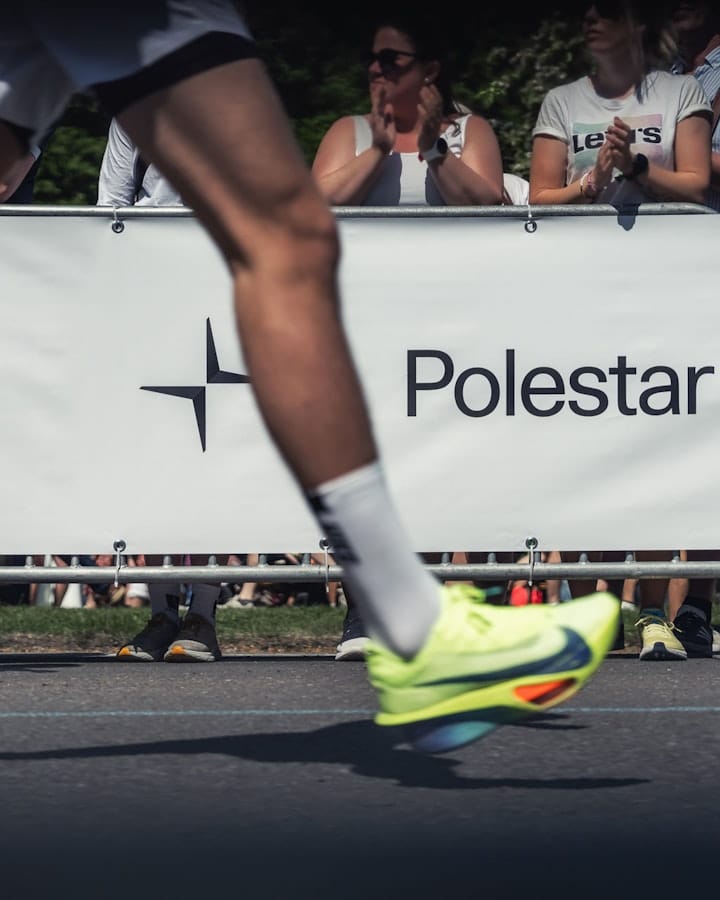A runner participating in the Göteborgsvarvet with a white banner displaying the text 'Polestar' behind him