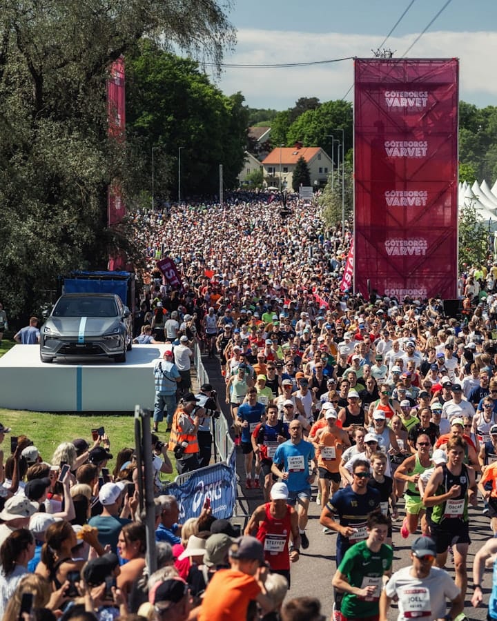 A sea of Göteborgsvarvet runners with a Polestar 2 on a podium to the lef