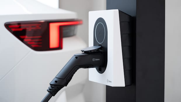 A white Zaptec Go wallbox mounted on the wall with a charging cable connected to it.