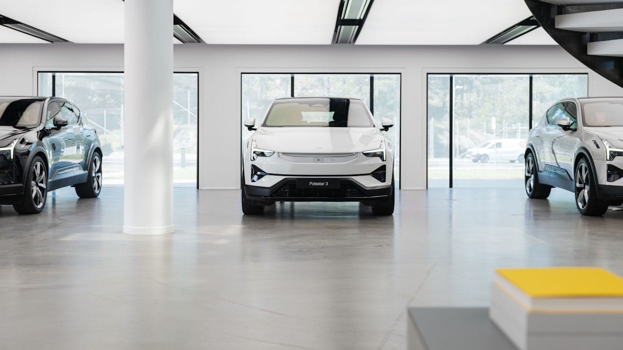 Three Polestar 3 cars in a row inside the Polestar HQ building, with one Polestar 3 in the middle and the other two on the sides