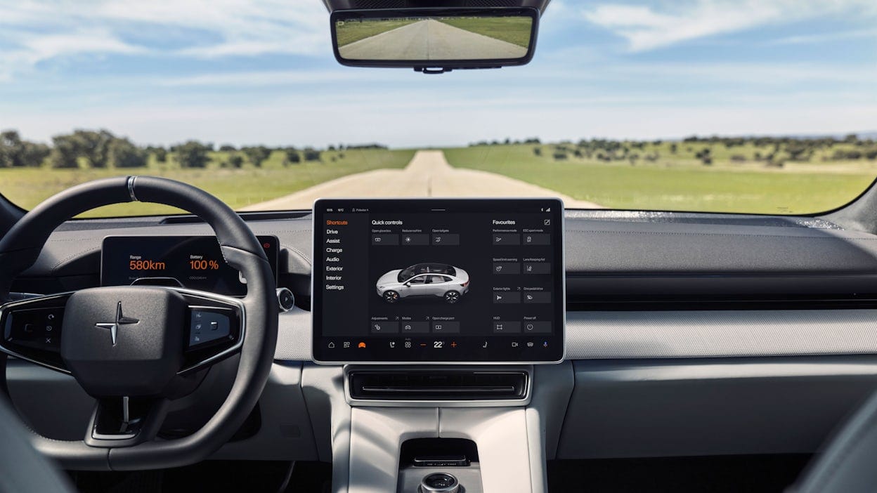 Inside a Polestar 4 showing the steering wheel and display with a view of a long country road