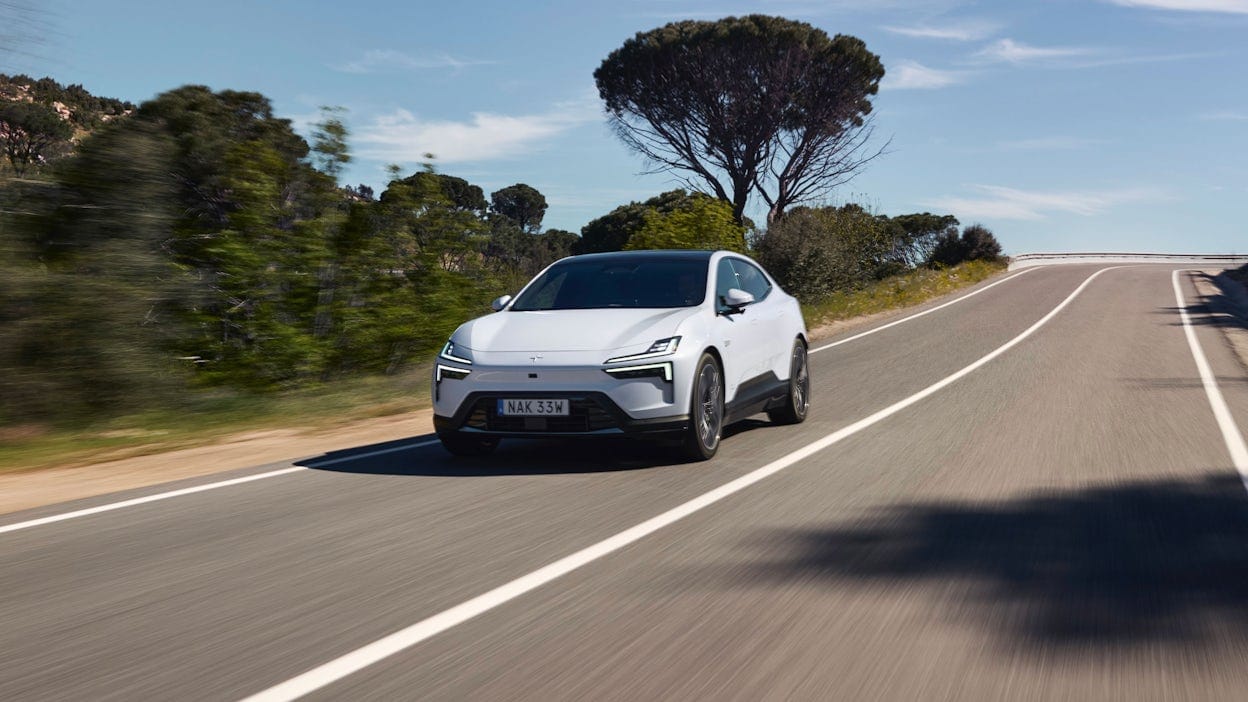 Front view of a Polestar 4 being test-driven on an asphalt road by the media