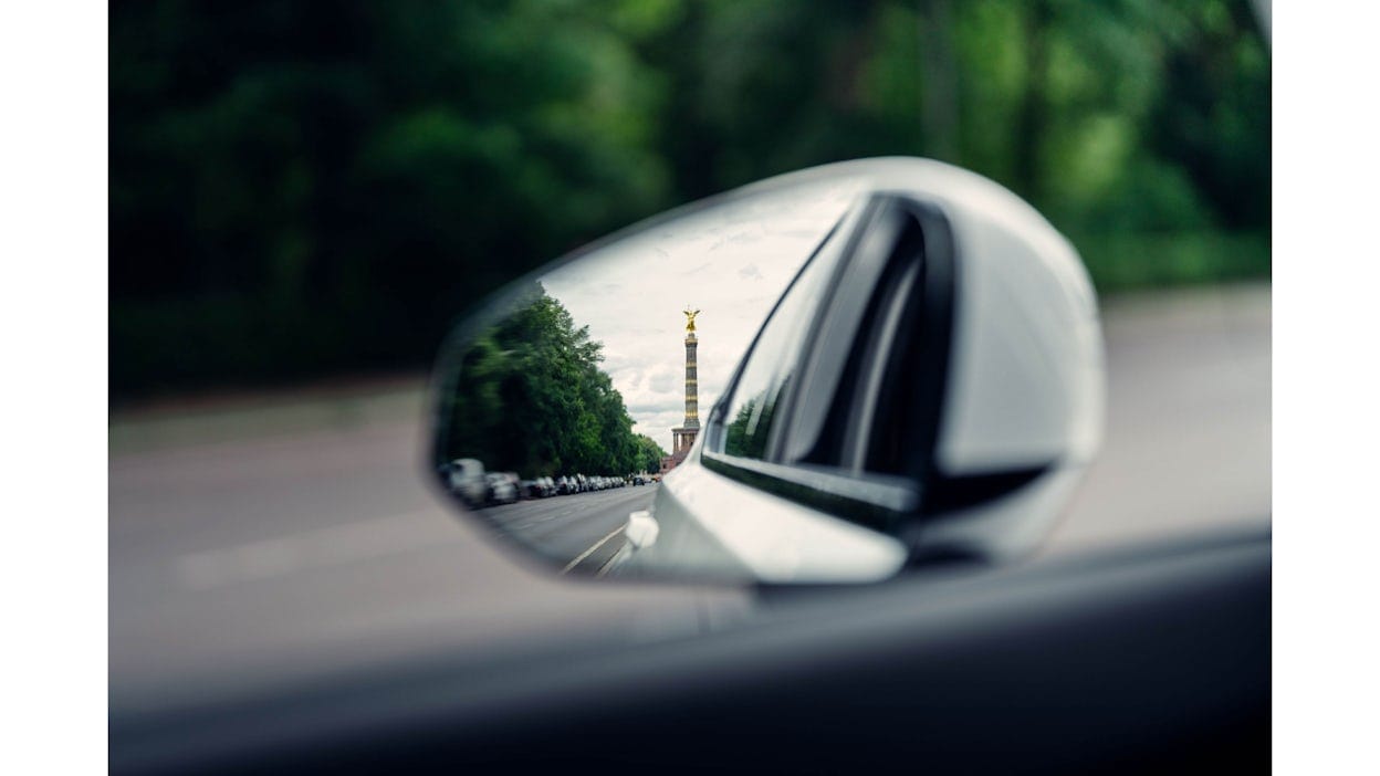 Victory column seen in Polestar 2's side mirror in the distance.