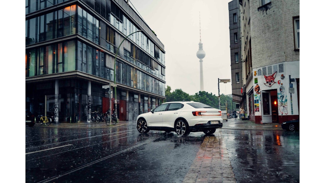 Witte elektrische Polestar 2 in de regen op een kruispunt