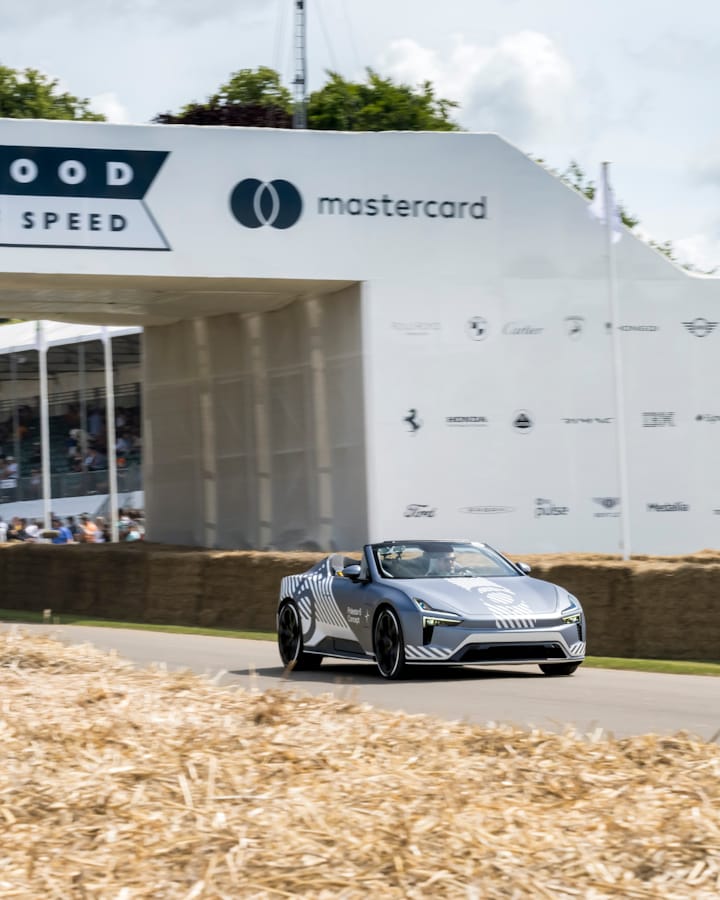 A Polestar 6 Concept driving down a track, with hay bales in the foreground and a white bridge with 'Goodwood Fesitval of Speed' written on it.