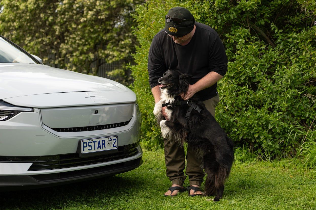 Stan pets his dog next to his Polestar 2 in his backyard