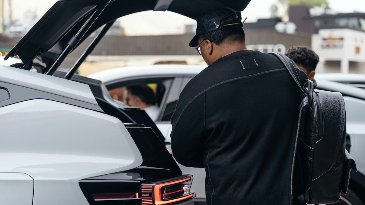 A journalist packing his gear into the trunk of a Polestar 3.